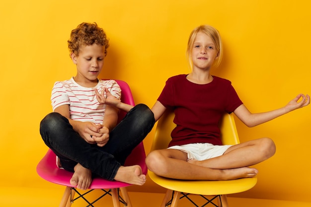 Dzieciństwo małych dzieci siedzących razem na krzesłach na kolorowym tle