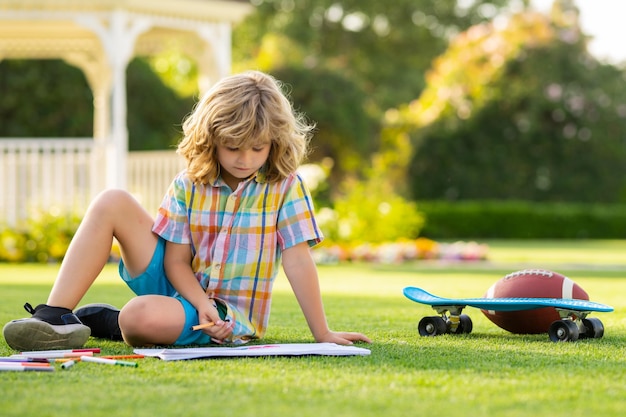 Dziecko artysta maluje kreatywność wakacje dzieciak chłopiec rysuje w parku kłaść w trawie bawić się na naturze b