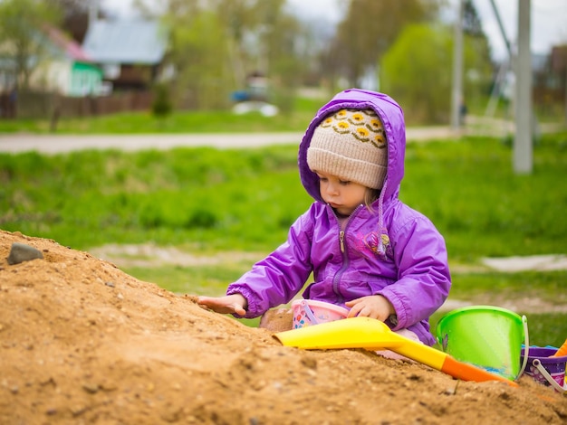 Dziecko bawi się w piasku łopatą i wiaderkiem
