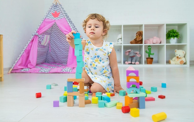 Dziecko bawi się w pokoju dziecięcym drewnianym konstruktorem Selektywna ostrość