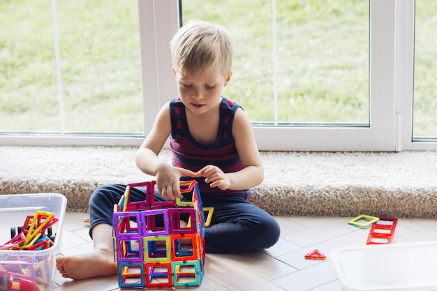 Dziecko bawi się wielokolorowym magnetycznym konstruktorem budującym wieżę zabawek edukacyjnych