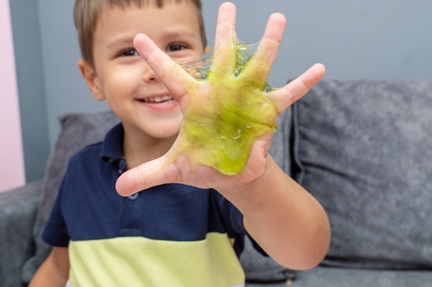 Dziecko bawiące się czerwonym śluzem, mazią, żelem w dłoniach