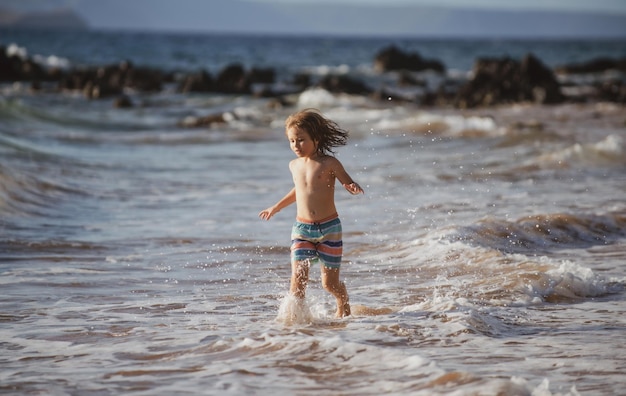 Dziecko biegające na plaży szczęśliwe dziecko biegające w morzu podczas letnich podróży wakacyjnych i przygody na morzu lub oceanie