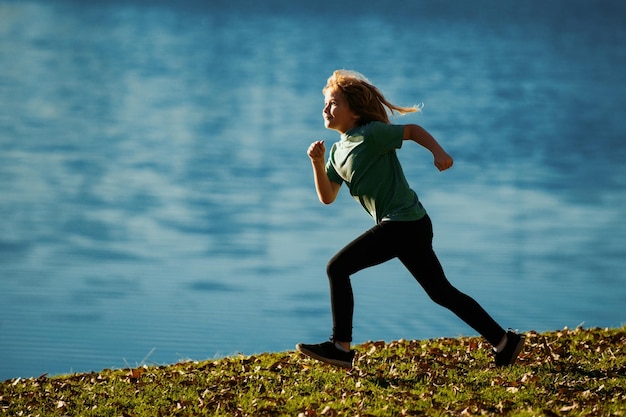 Zdjęcie dziecko biegnące przez wodę w pobliżu brzegu wzdłuż jeziora sportowe małe dziecko biegające i trenujące ou