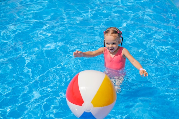 Dziecko biegnie za nadmuchiwaną piłką na wodzie w basenie
