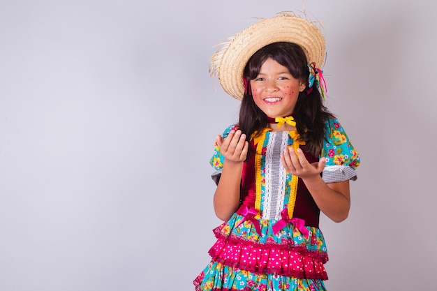 Dziecko brazylijska dziewczyna z ubraniami Festa Junina zapraszając rękami