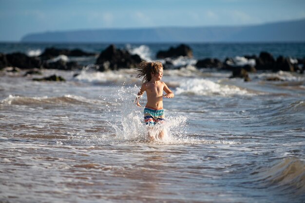 Dziecko chłopiec na wybrzeżu małe dziecko bawiące się w oceanie wakacje nad morzem dziecko falami