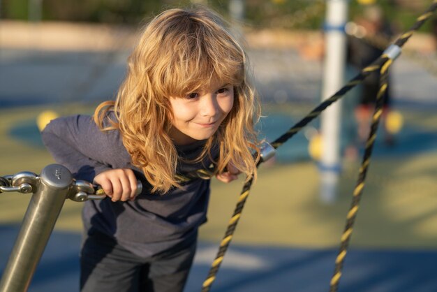 Dziecko chłopiec wspinający się po sieci chłopiec bawiący się na placu zabaw dla dzieci aktywne małe dziecko na placu zabaw