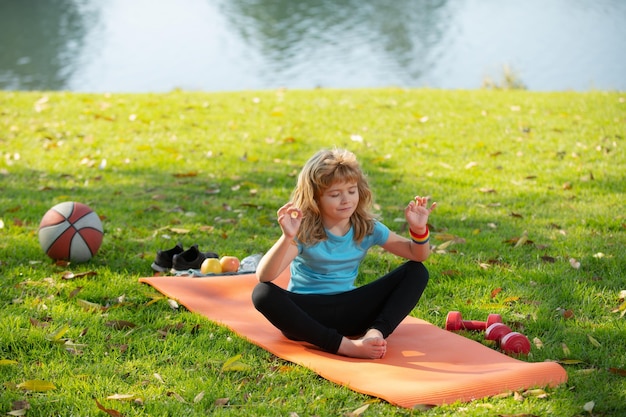 Dziecko ćwiczące jogę ćwiczące w sportowej koszulce joga na świeżym powietrzu w pozycji lotosu Dzieci medytujące podczas jogi