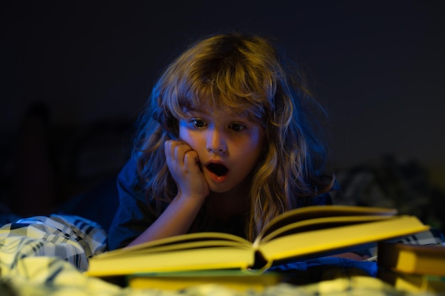 Dziecko czyta książkę o ekscydach Mały chłopiec ogląda zdjęcia w książce z bajkami Dziecko odrabia zadanie domowe dla szkoły podstawowej Nauka dzieci Rozwój dziecka Sprytny podekscytowany chłopiec