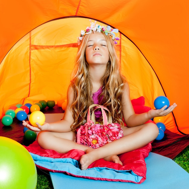 Dziecko dziewczyna wśrodku campingowego namiotu relaksuje z joga