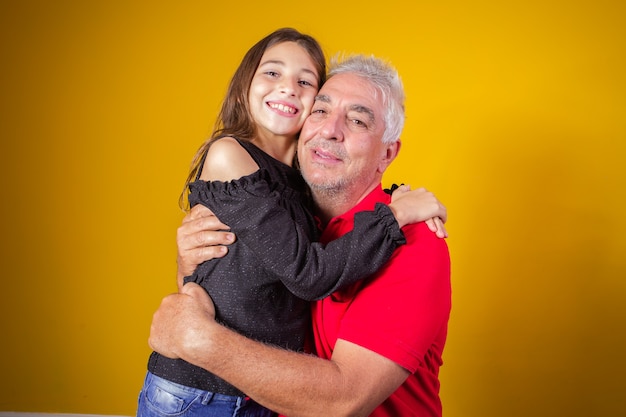 Dziecko dziewczynka przytulanie dziadka. Ojciec i córka na żółtym tle. Dzień Ojca. dzień dziadka