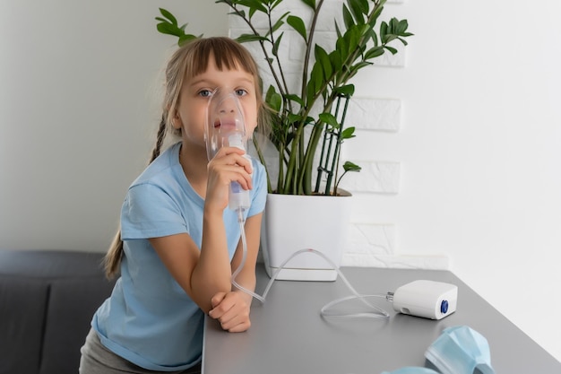 Dziecko dziewczynka robi inhalację za pomocą nebulizatora. chore dziecko trzyma w ręku inhalator i oddycha przez inhalator w domu.