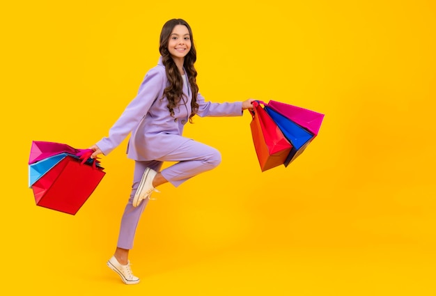Dziecko dziewczynka trzyma torbę na zakupy cieszącą się sprzedażą na białym tle Biegnij i skacz Portret nastolatka jest gotowa na zakupy