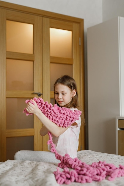 Dziecko dziewczynka trzymająca na drutach siedząc na łóżku w sypialni w domu