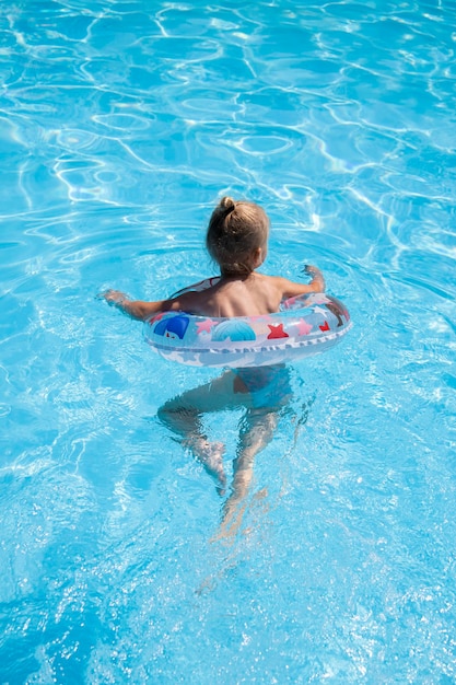 Dziecko dziewczynka uczy się pływać z nadmuchiwanym pierścionkiem w basenie