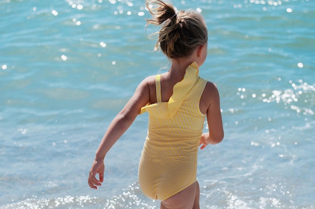 Dziecko dziewczynka w żółtym stroju kąpielowym w morzu