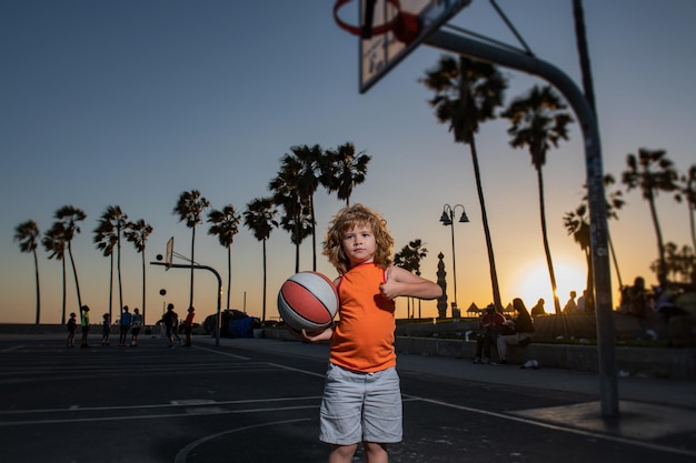Dziecko gry w koszykówkę trzymając piłkę z kciuki do góry znak.