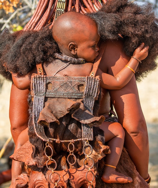 Zdjęcie dziecko himba za plecami matki.