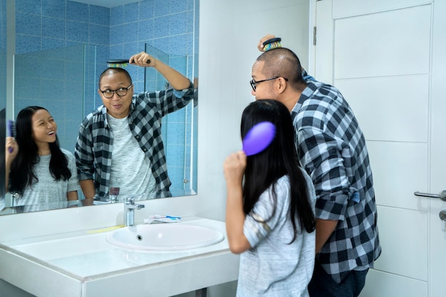 Dziecko i ojciec czeszą włosy przed lustrem