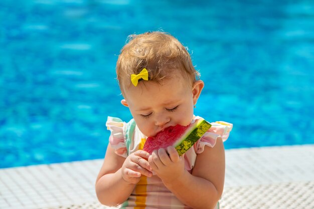Dziecko je arbuza przy basenie. Selektywne skupienie. Dzieci.
