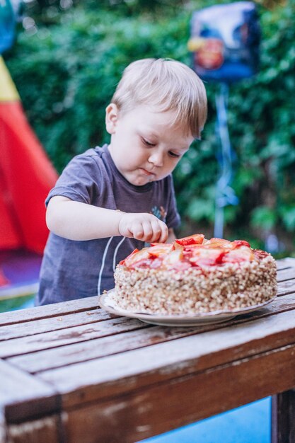 Dziecko je ciasto i dmucha świece na przyjęciu urodzinowym.