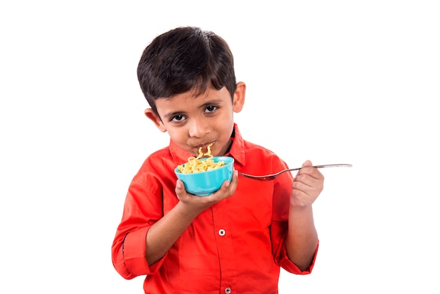 Dziecko jedzenie makaronu, Indian Kid jedzenie makaronu z widelcem na białej ścianie