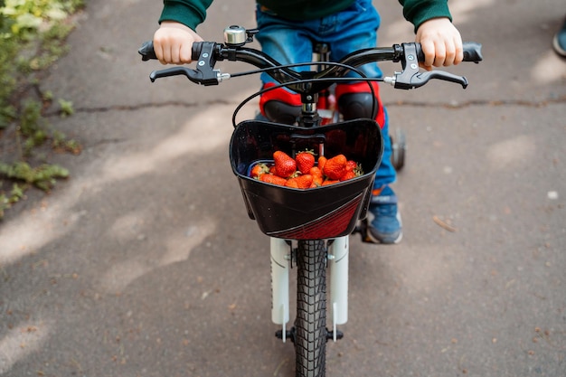 Dziecko jedzie na rowerze z koszem pomidorów.