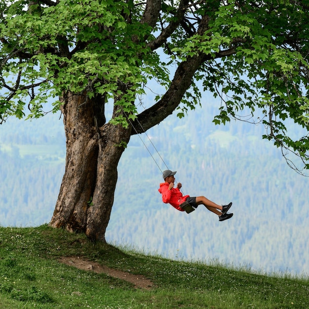 Dziecko jeździ na huśtawce wysoko w górach drzewo i huśtawka