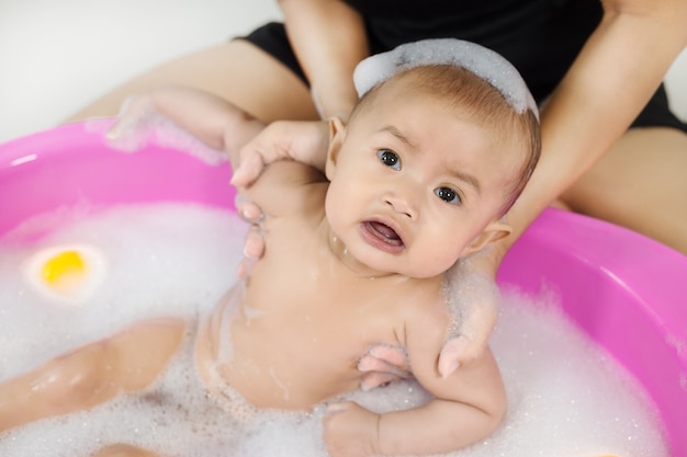 dziecko kąpiące się w wannie i bawiące się piankowymi bańkami