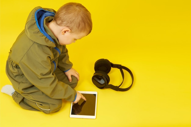 Dziecko korzysta z cyfrowego tabletu i bezprzewodowych słuchawek