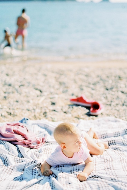 Dziecko leży na brzuchu na kocu na plaży