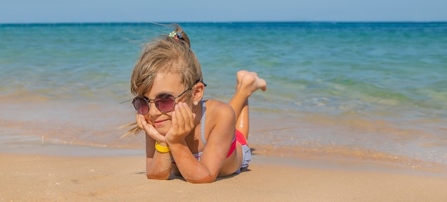 Dziecko leży w piasku na plaży.