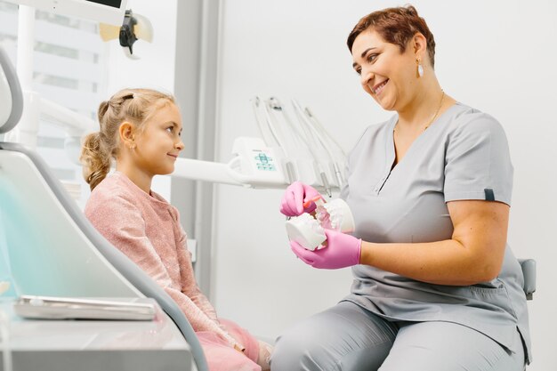 Dziecko ma stomatologicznego czek up kobieta specjalistą w dentysty biurze
