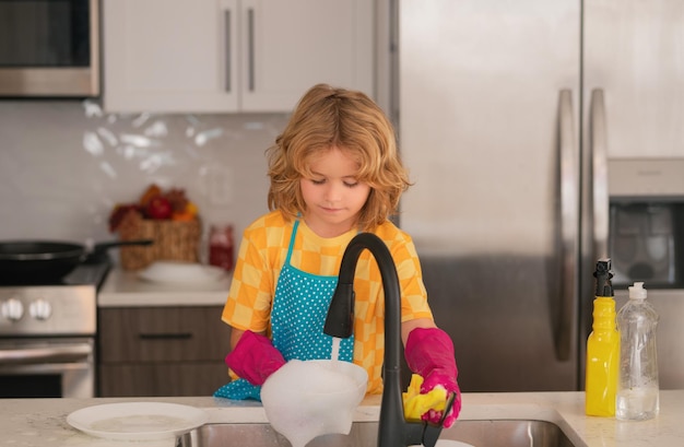 Zdjęcie dziecko myje naczynia w kuchni wnętrze dziecko pomaga w pracach domowych sprzątanie i dom