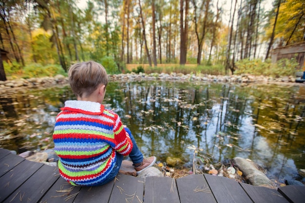 Dziecko na jesiennym spacerze Chłopiec siedzi na tle jesiennej przyrody