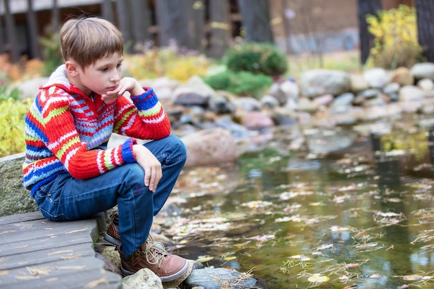 Dziecko na jesiennym spacerze Smutny chłopiec nad jeziorem