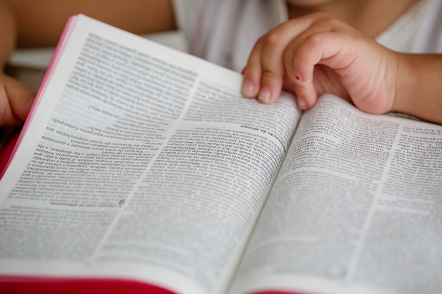 Dziecko na stole czyta Biblię i ją przegląda