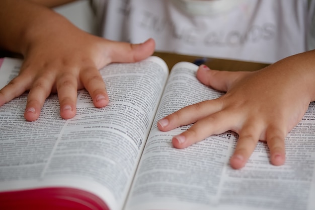 Dziecko na stole czyta Biblię i ją przegląda
