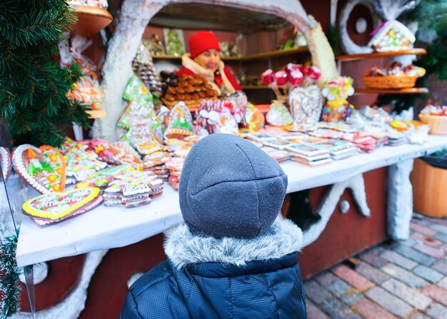 Dziecko na straganie na jarmarku bożonarodzeniowym na placu Dome na Starym Mieście w Rydze zimą