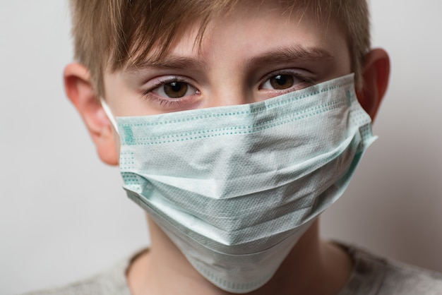 Dziecko nosi ochronną maskę medyczną, aby chronić go przed koronawirusem. Chłopiec z medyczną maską na jego twarzy.