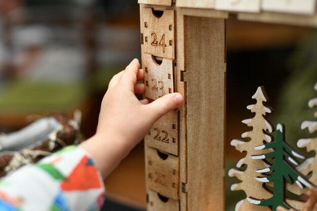 Dziecko otwiera drewniany kalendarz adwentowy z prezentami