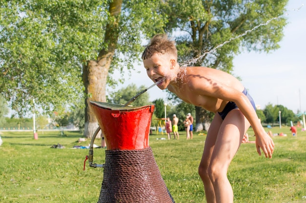 Zdjęcie dziecko pije wodę na plaży.