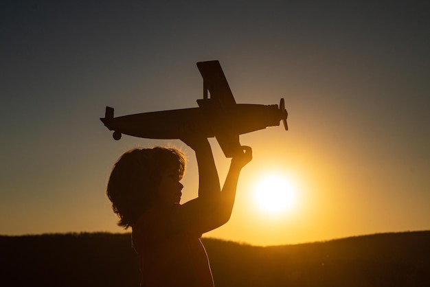 Dziecko pilot-lotnik z samolocikiem marzy o podróżowaniu latem na łonie natury o zachodzie słońca