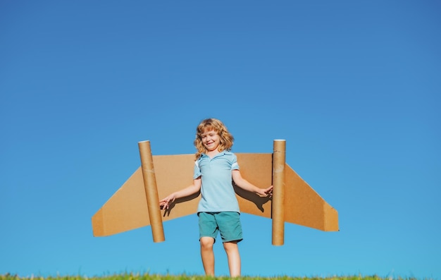 Zdjęcie dziecko pilot z zabawkowym plecakiem odrzutowym na tle nieba szczęśliwe dziecko bawiące się na zewnątrz szczęśliwe dzieciństwo