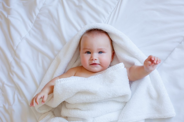 Dziecko po kąpieli zawinięte w ręcznik leżący na łóżku