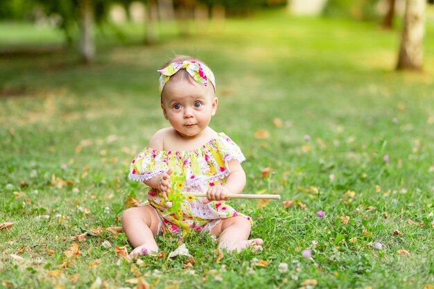 Dziecko po trawniku chodzi latem w żółtym ubranku