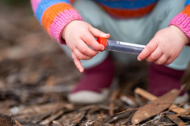 dziecko robi naukę maluch z probówkami na zewnątrz, w naturalnym środowisku, w krzakach