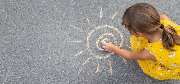 Dziecko rysuje słońce na asfalcie. Selektywna ostrość.