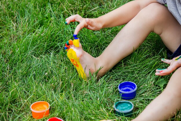 Dziecko rysuje wzór na nodze. Zabawny rysunek z jasnymi kolorami na ciele. Selektywne skupienie